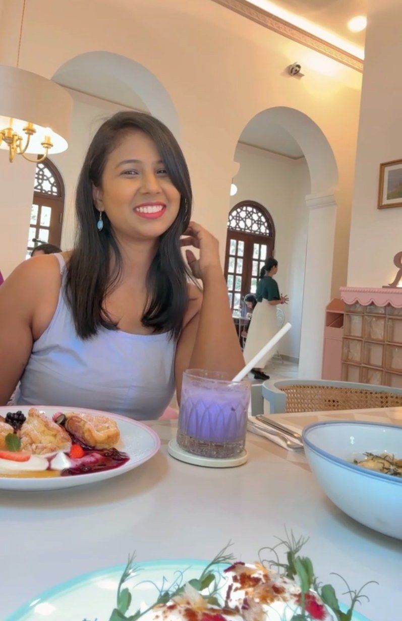 Smiling at a café table with a purple drink