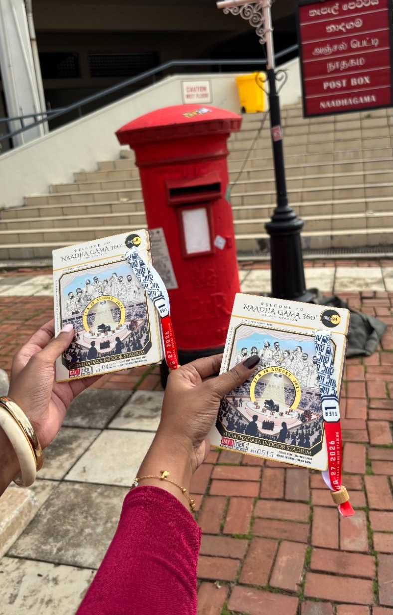 Holding concert tickets and wristbands by a red post box